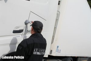 policyjny technik zabezpiecza ślady na drzwiach pojazdu ciężarowego