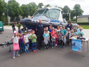 grupa dzieci z policjantką przy łodzi policyjnej
