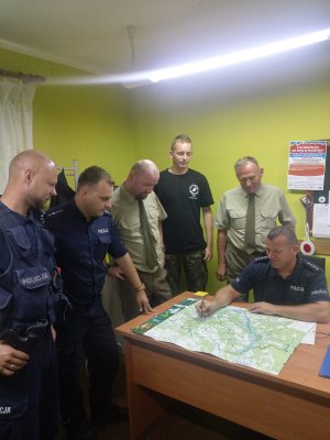 policjanci i strażnicy leśni przy mapie