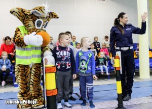 policjantka i dzieci z maskotką przechodzą przez pasy