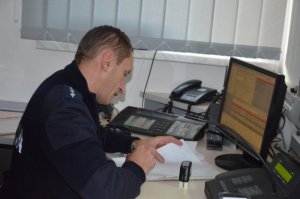 policjant siedzący przy biurku i sporządzający dokumentację służbową