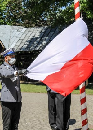 policjanci wciągają flagę państwową na maszt