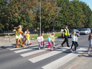 dzieci z podniesionymi rękami przechodzą przez przejście dla pieszych