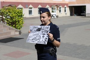 Policjantka pokazuje dzieciom ilustracje dotyczące bezpieczeństwa nad wodą