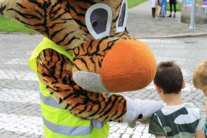 policyjny tygrysek lupo stoi przy przejściu dla pieszych wraz z dzieckiem