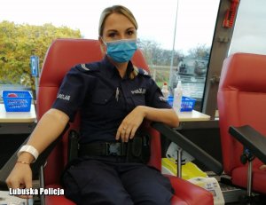 policjantka siedząca na fotelu w trakcie oddawania krwi