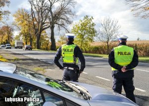 policjanci z wydziału ruchu drogowego stojący przy drodze - nadzorują ruch