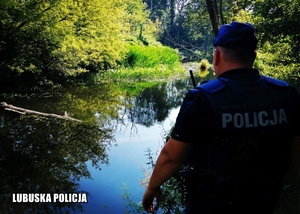 policjant stojący tyłem patrzący w stronę rzeki