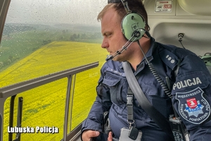 Policjant wygląda przez okno helikoptera