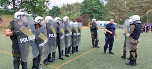 uczniowie klas mundurowych ubrani w policyjną odzież antyuderzeniową. W dłoniach trzymają tarcze ochronne z napisem Policja