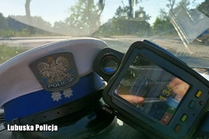 policyjna czapka i urządzenie do pomiaru prędkości na kokpicie pojazdu
