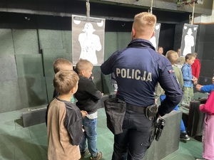 policjant pokazuje dzieciom strzelnicę